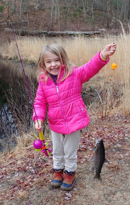 Young girl smiling with a freshly caught rainbow trout